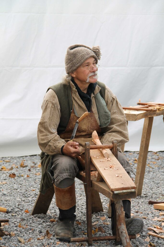 A man in brown jacket and hat sitting on chair.