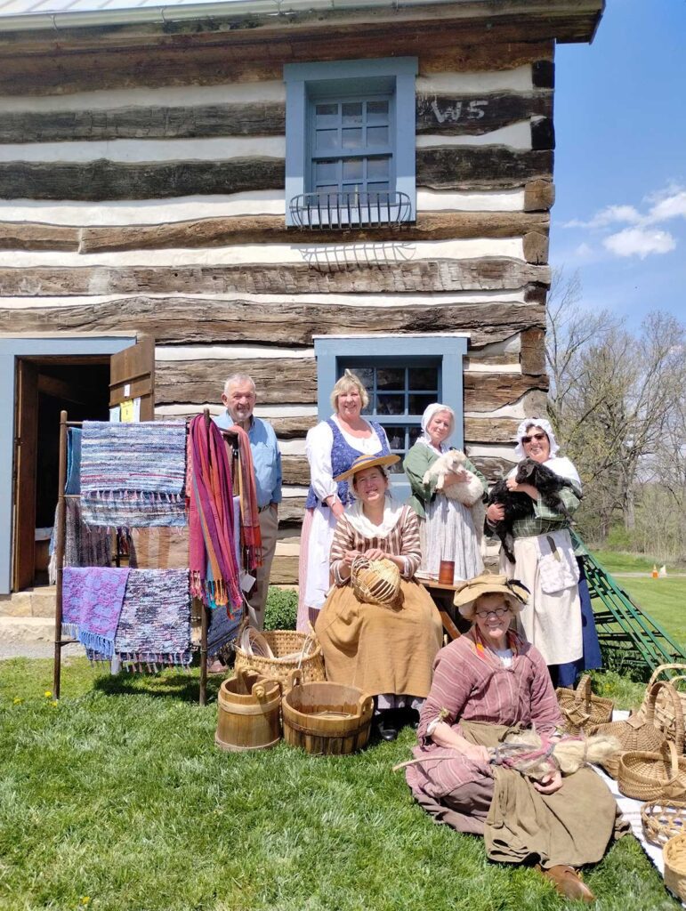 A group of people standing around in front of a log cabin.