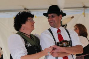 A man and woman wearing lederhosen dancing together.